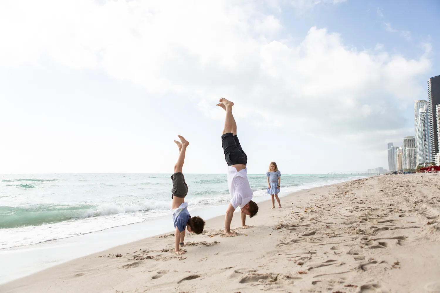 Father and son doing handstands on the beach